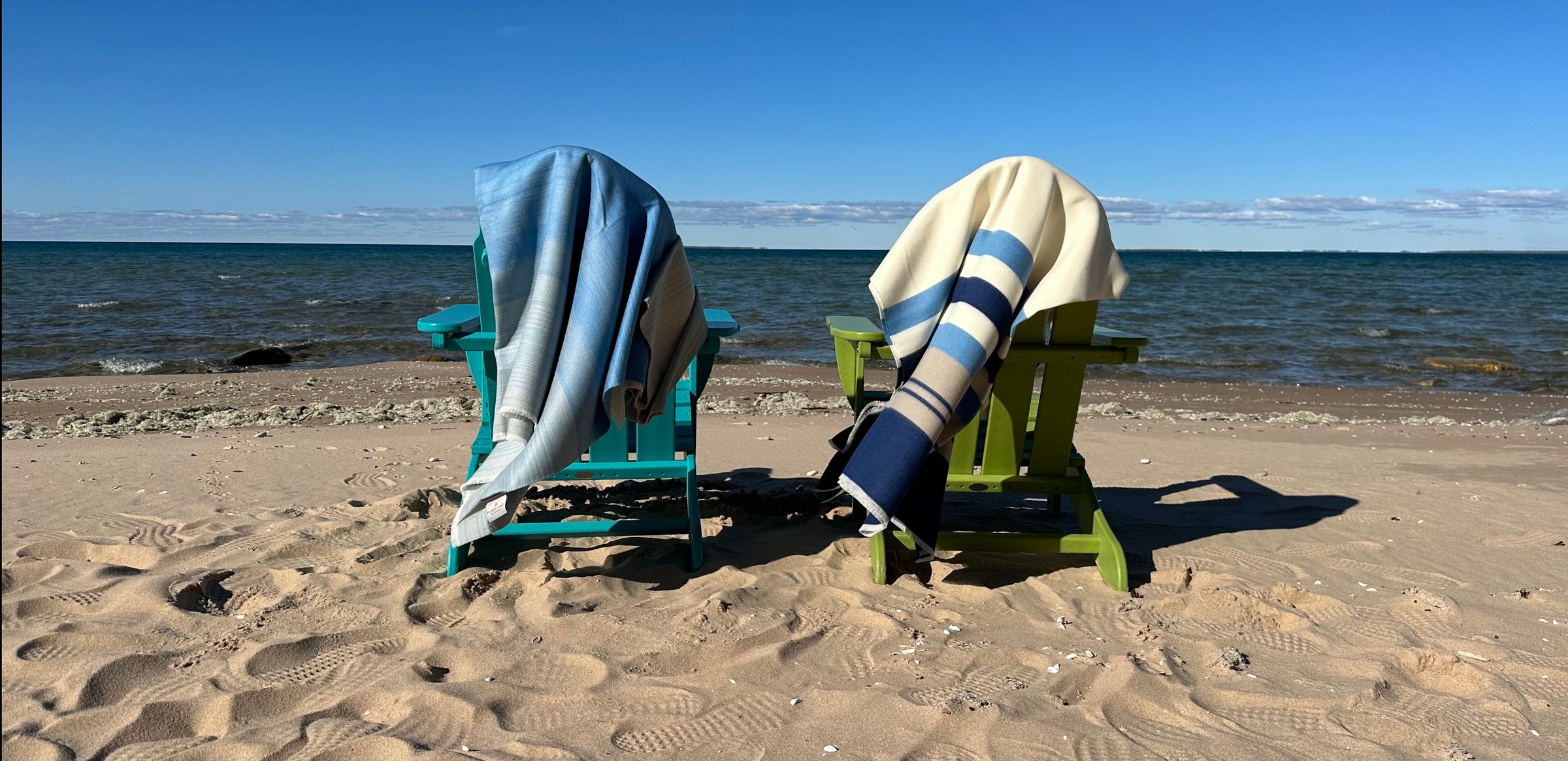 MaterialWorld.design German-made outdoor performance throw draped over a green Adirondack chair on a sandy beach, showcasing bleach-cleanable, mold-resistant fair-trade craftsmanship