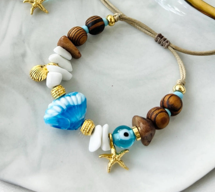 Scallop shell bracelet with wooden beads and gold charms.