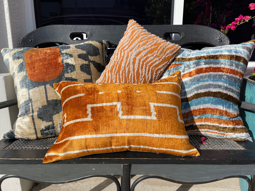 Material World warm-tone handwoven throw pillows in orange and blue stripes, featured for cozy, ethical home décor at materialworld.design