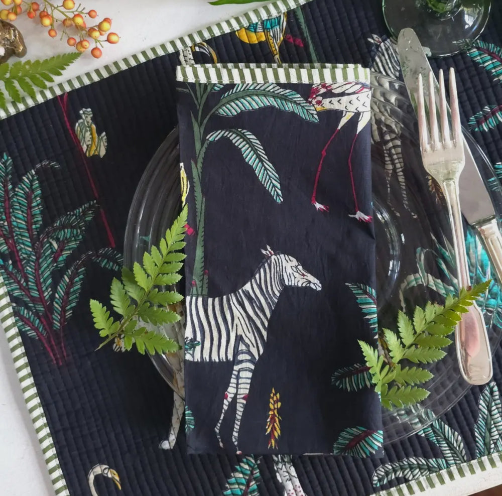 Material World black tablecloth with zebra print and green fern accents, highlighting sustainable artisan textiles